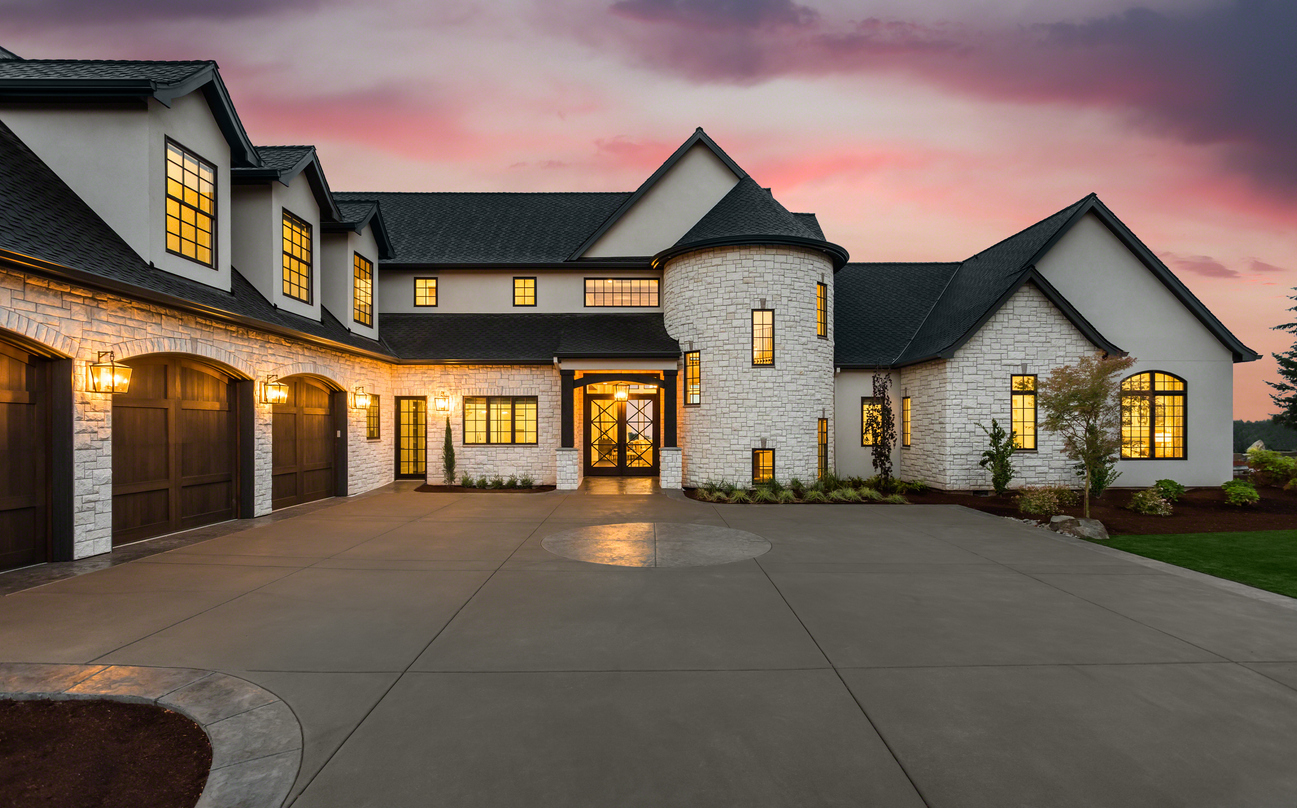 new luxury home with three car garage, large driveway and glowing exterior and interior lights